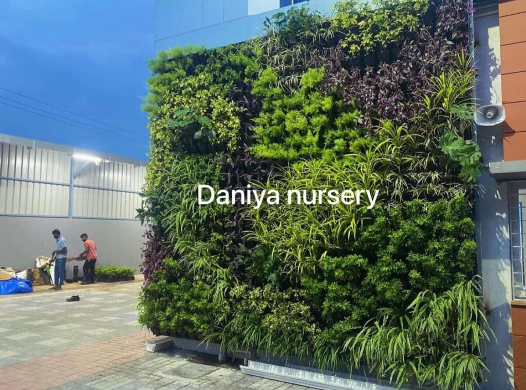 Outdoor vertical garden wall with dense green and purple foliage, installed beside a building under a clear sky